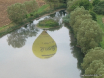 Reflectie van de ballon in het water bij ballonvaart